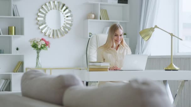 Mulher sorridente bonita com laptop no escritório em casa. Menina atraente jovem comunicando com os amigos — Vídeo de Stock