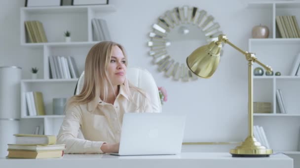 Chica pensante con portátil en el escritorio de la oficina en casa. Mujer joven con portátil en casa — Vídeos de Stock