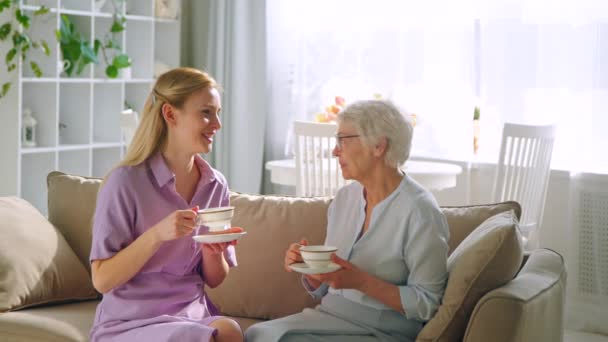 Junge Tochter und ältere Mutter mit Tassen Tee zu Hause — Stockvideo
