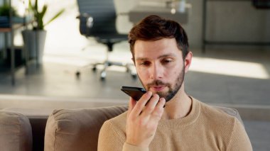 Genç adam telefonda bir sesli mesaj kaydediyor.