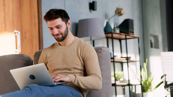 Портрет усміхненого чоловіка з ноутбуком, що сидить на дивані — стокове фото