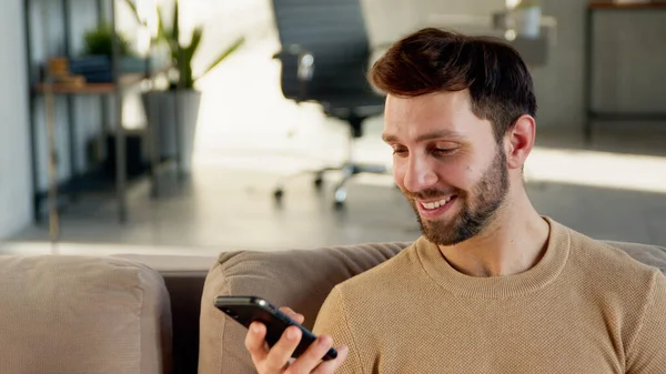 Усміхнений студент зі смартфоном вдома — стокове фото