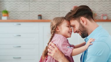 Genç baba evde küçük kızına sarılıyor. Şefkat
