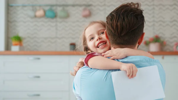 Bonito menina abraçando papai na sala de estar — Fotografia de Stock