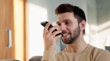 Genç bir erkek telefonda bir sesli mesaj kaydediyor.