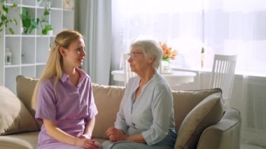 Genç bir kız ve yaşlı bir kadın parlak bir odada kanepede konuşuyorlar.