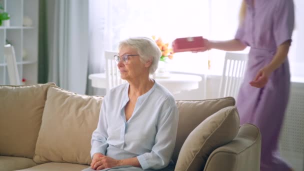 Jong blond vrouw geeft kleine doos met cadeau met vrolijke glimlach op verjaardag — Stockvideo