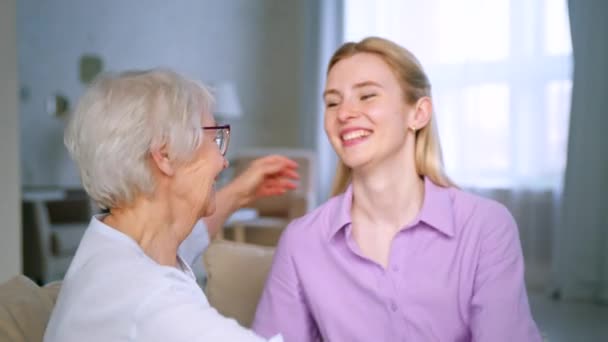 Jovencita y anciana abrazando y mirando a la cámara con una sonrisa — Vídeo de stock