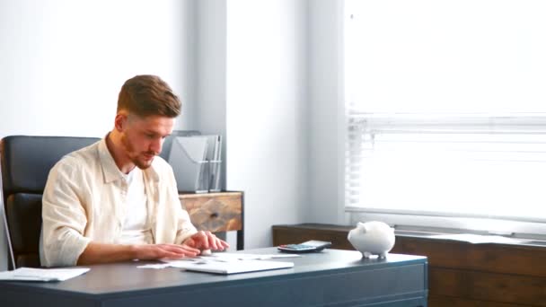Guy analyst with beard gathers small checks on grey table — Stock Video