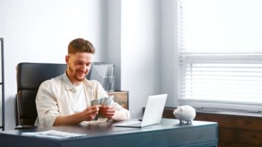 Sakallı, gülümseyen şirket müdürü ellerinde dolar sayıyor.