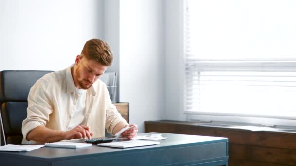 Bearded accountant sums up checks recording in notebook — Stock Video