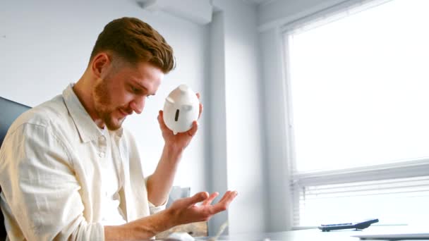 Joyful company manager with beard takes piggy bank with coin — Stock Video