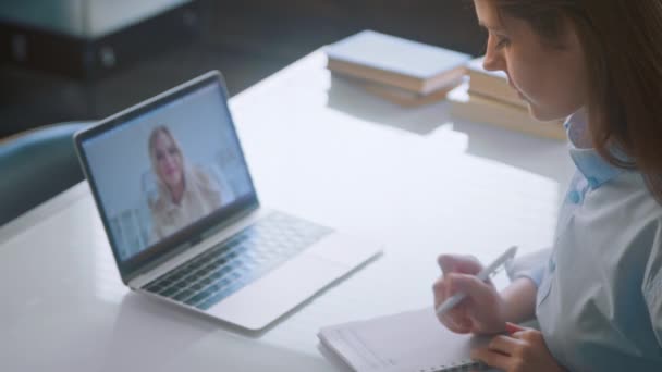 Lady doctor writes in notebook listening to online patient — Stok video