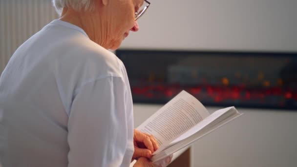 Señora de edad con pelo gris corto y gafas lee libro — Vídeo de stock
