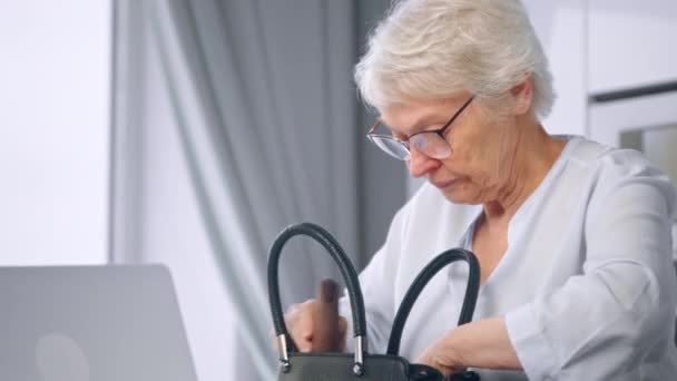 Verouderde zakenvrouw rommelt in de tas en keert terug naar het werk — Stockvideo