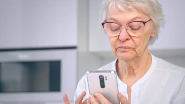 Mulher idosa gerente em óculos pergaminhos mídia social no telefone — Vídeo de Stock