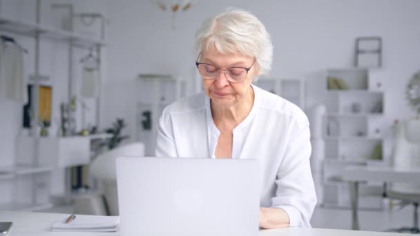 Concentrated old businesswoman in blouse types on laptop — Stok video