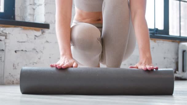 Грациозная женщина разворачивает резиновый коврик для тренировки в студии — стоковое видео