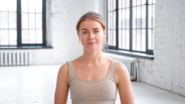 Attraktive Frau im Trainingsanzug lächelt im Studio in die Kamera — Stockvideo