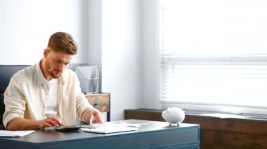 Bearded analytic accountant sums up small paper receipts