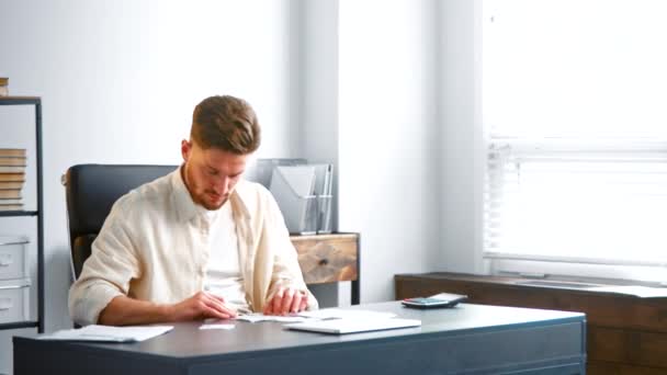 Männlicher Manager-Assistent mit Bart sortiert Schecks am Tisch — Stockvideo