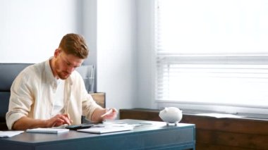 Professional accountant with beard sums up paper checks