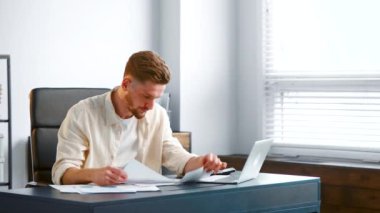 Company director examines reports and puts hands on head