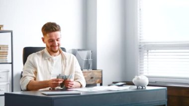 Smiling businessman with beard counts income money cash