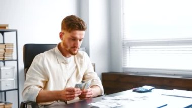 Company director in yellow shirt takes dollar banknotes