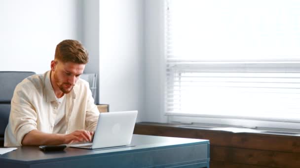 Concentrated manager in yellow shirt types on white laptop — Αρχείο Βίντεο