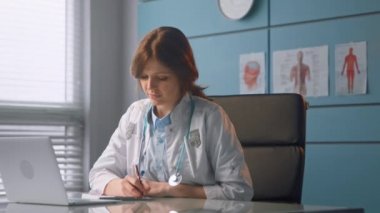 Esmer pratisyen doktor dizüstü bilgisayara baktığını yazmış.