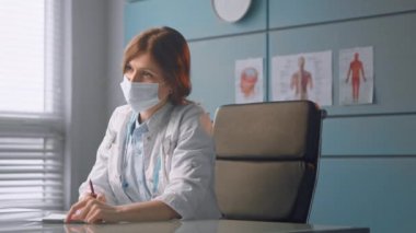 Tek kullanımlık beyaz maskeli kadın pratisyen.
