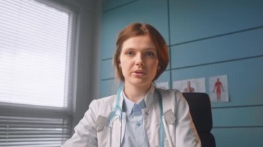 Palto giyen ciddi bir doktor online toplantıda hastayla konuşuyor.