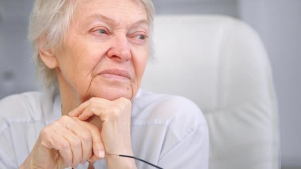 Pensativo sabia anciana con pelo gris corto mira a un lado — Vídeo de stock