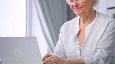 Professional woman secretary types on grey laptop and smiles