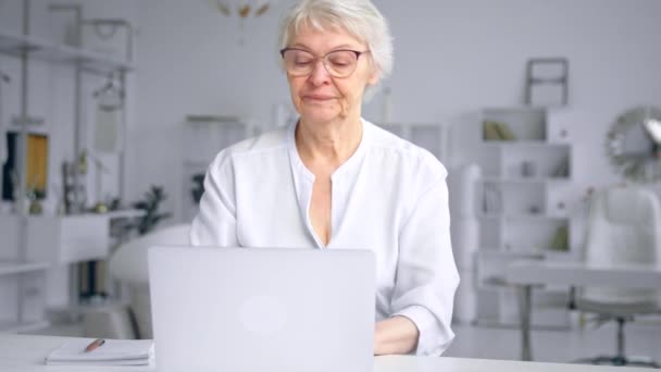 Serious aged lady secretary types on laptop closes computer — Stok video