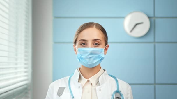 Young woman general practitioner in coat and face mask — Stok Video