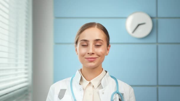 Молодая женщина врач общей практики в пальто со стетоскопом — стоковое видео