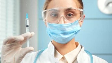 Concentrated young woman general practitioner holds syringe