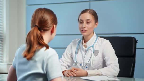 Blond ung kvinna läkare talar med patienten på sjukhuset — Stockvideo