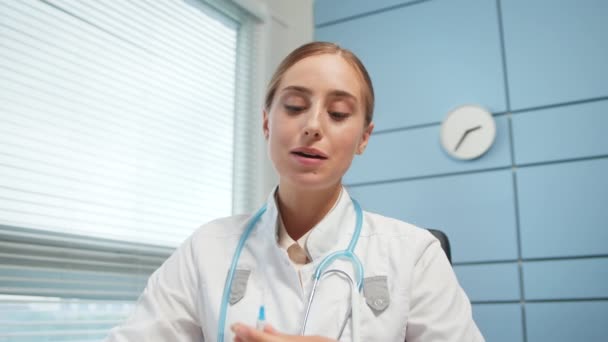 Junge Medizinbloggerin im weißen Kittel zeigt Spritze — Stockvideo