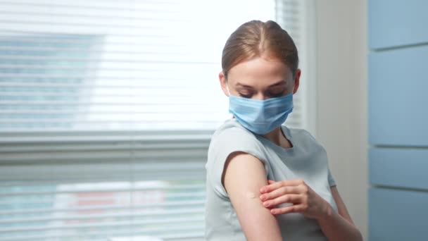 Jonge vrouw blond in blauw masker kijkt naar injectieplek — Stockvideo