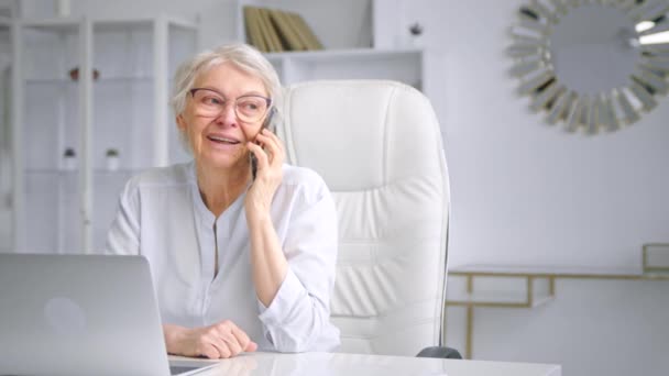 Sonriente anciana gerente corporativo habla en el teléfono inteligente azul — Vídeos de Stock