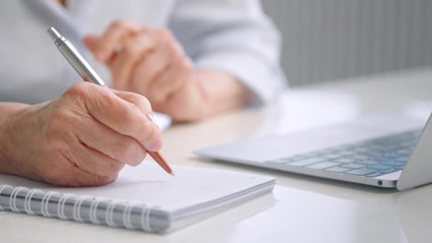 Senior lady teacher holds hand with pen over pad page close — Stock Video