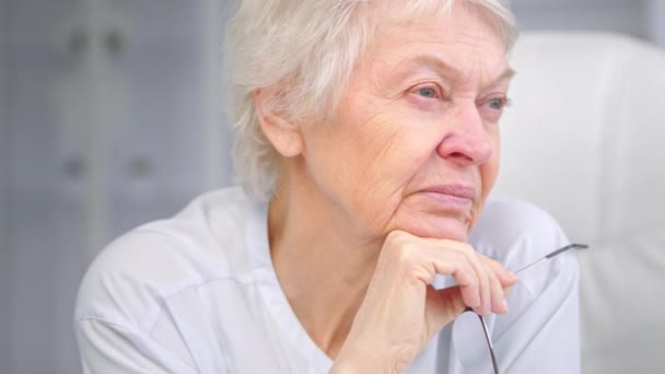 Abuela mayor con pelo gris corto sostiene gafas — Vídeos de Stock