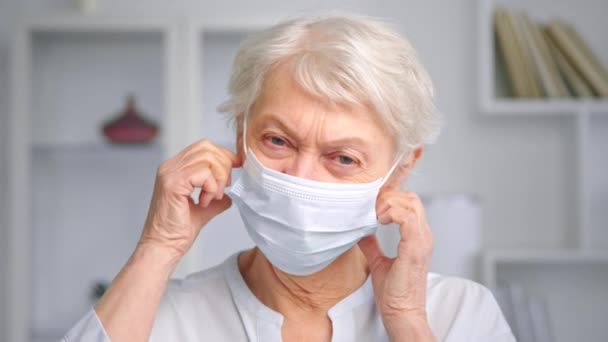 Mulher velha gerente leva branco descartável máscara facial fora — Vídeo de Stock