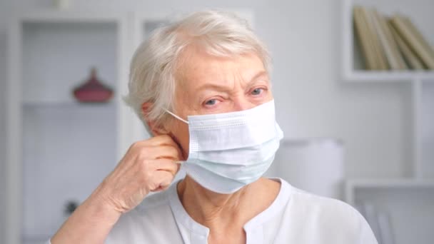 Serious señora de edad se quita la mascarilla desechable blanco — Vídeos de Stock