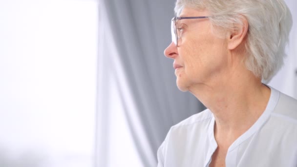 Thoughtful old woman with short grey hair and glasses — Stock Video