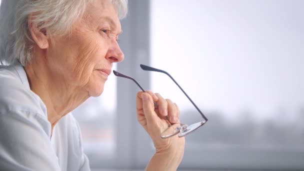 Serious senior businesswoman with grey hair holds glasses — Stock Video