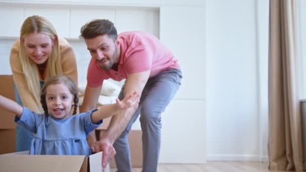 Alegre padres jugar con la pequeña hija moviendo niño en caja — Vídeos de Stock